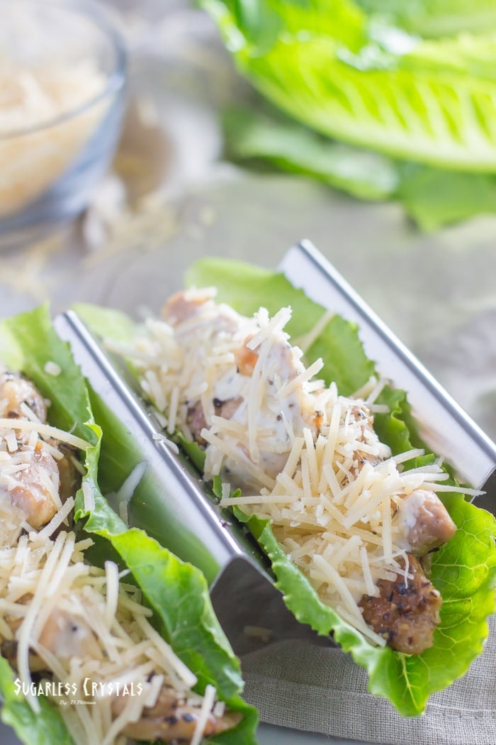 two low carb caesar chicken lettuce wraps with caesar dressing and parmesan cheese