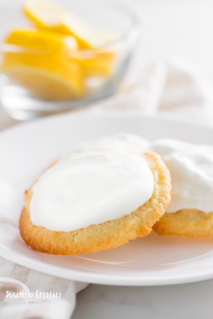 Lemon keto cookies on a plate with a bowl of lemons in the background