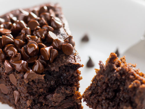 keto chocolate cake with chocolate chips on top on a plate