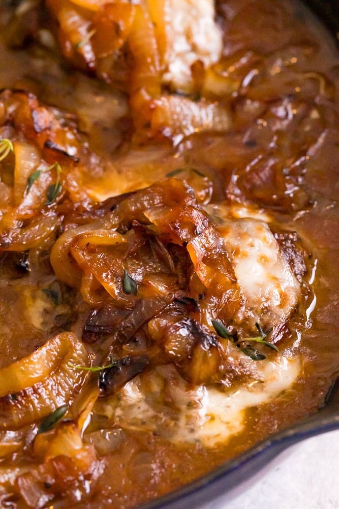 French onion hamburger steak being served in pan with melted cheese