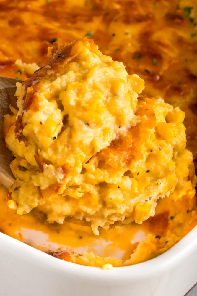 Velveeta cheesy corn casserole scooped from the baking dish to serve