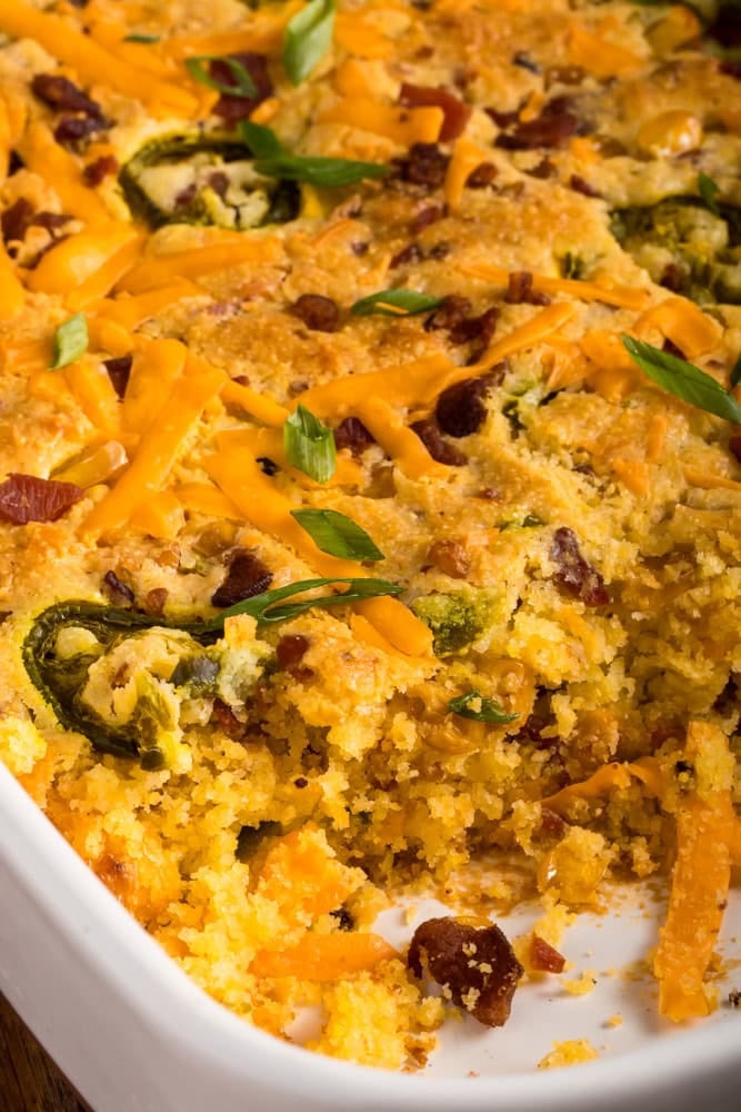 Inside of the loaded cornbread casserole dish after a piece has been removed