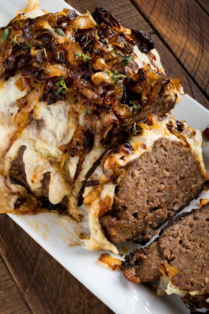 French onion meatloaf served on platter top sliced with cheese and caramelized onions on top