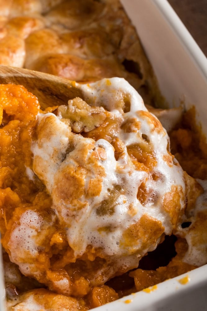 candied sweet potato casserole being scooped from the baking dish for serving.