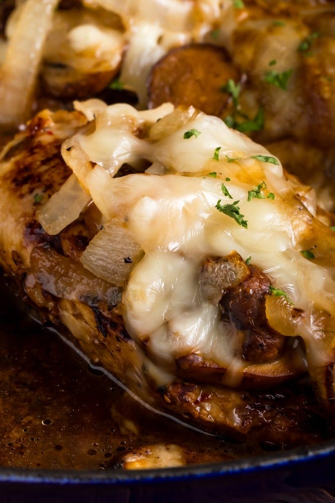close up of Texas Roadhouse smothered chicken in pan smothered with onions and mushrooms and Jack cheese