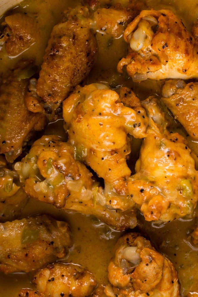 overhead close up of smothered chicken wings in Dutch oven