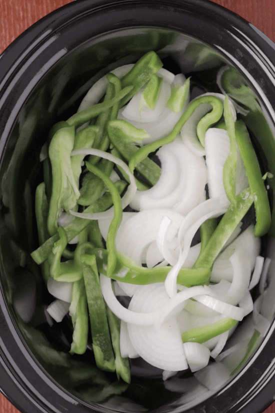 Step 2: Sliced onions and green bell peppers added to the crockpot for turkey wings