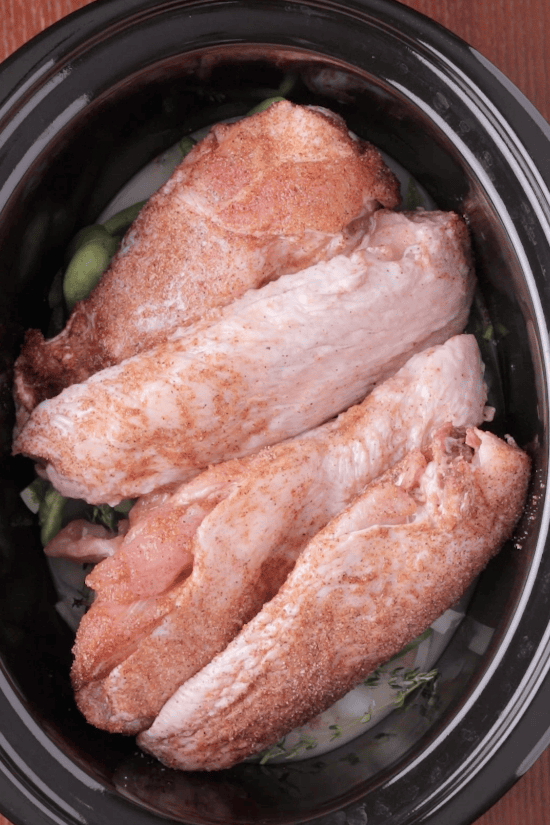Step 3: Seasoned turkey wings arranged over onions and green peppers in the crockpot