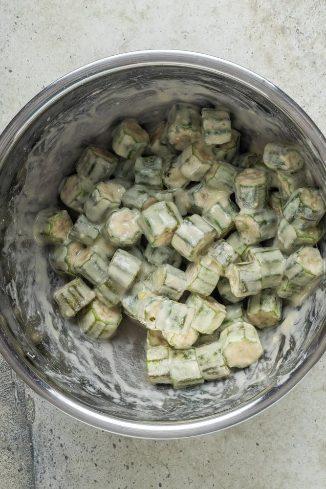Floured okra coated in a buttermilk and egg wash before breading.