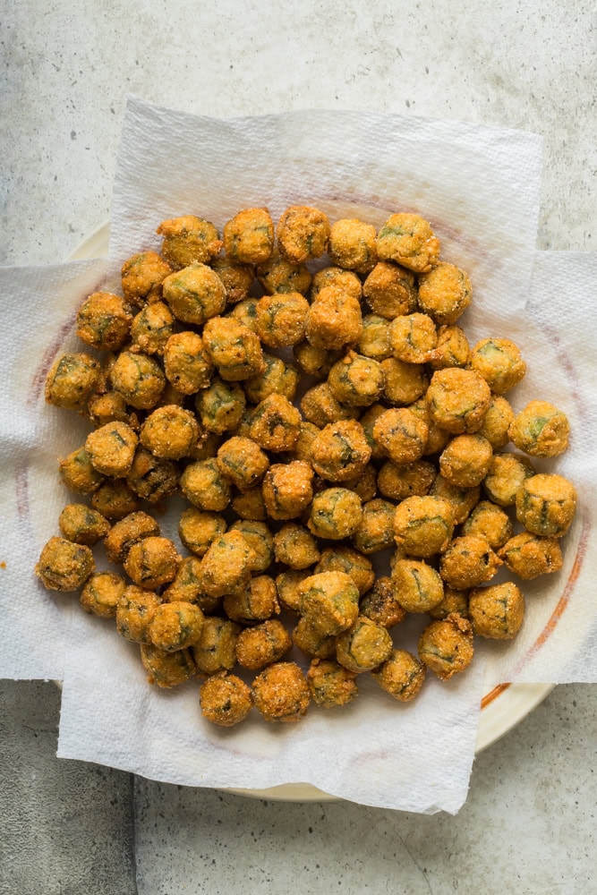 Freshly fried okra draining on paper towels after cooking until golden brown.