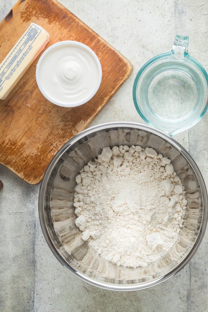 Ingredients for homemade 7UP biscuits, including biscuit mix, sour cream, lemon-lime soda, and salted butter.
