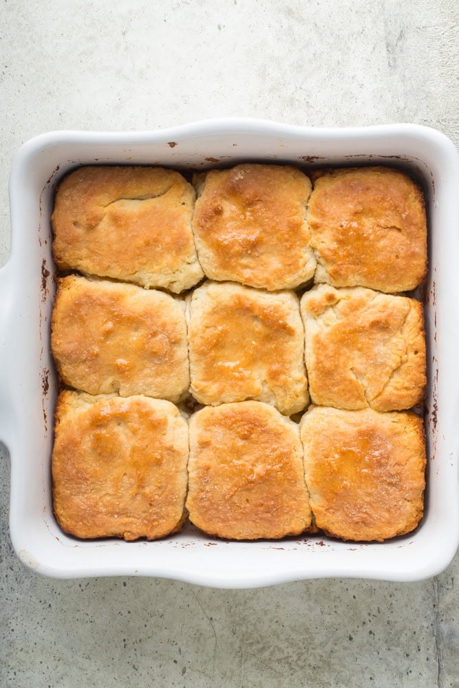 Overhead view of nine golden-brown 7UP biscuits baked together in a square white baking dish.