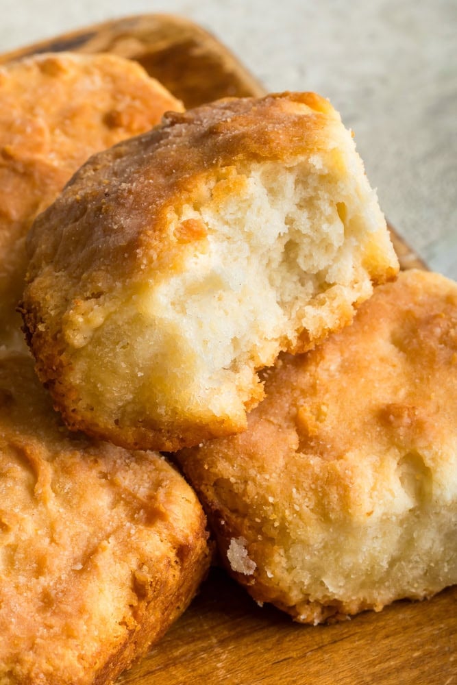 7UP biscuit broken open to show its soft, fluffy interior and golden-brown crust, surrounded by freshly baked biscuits.