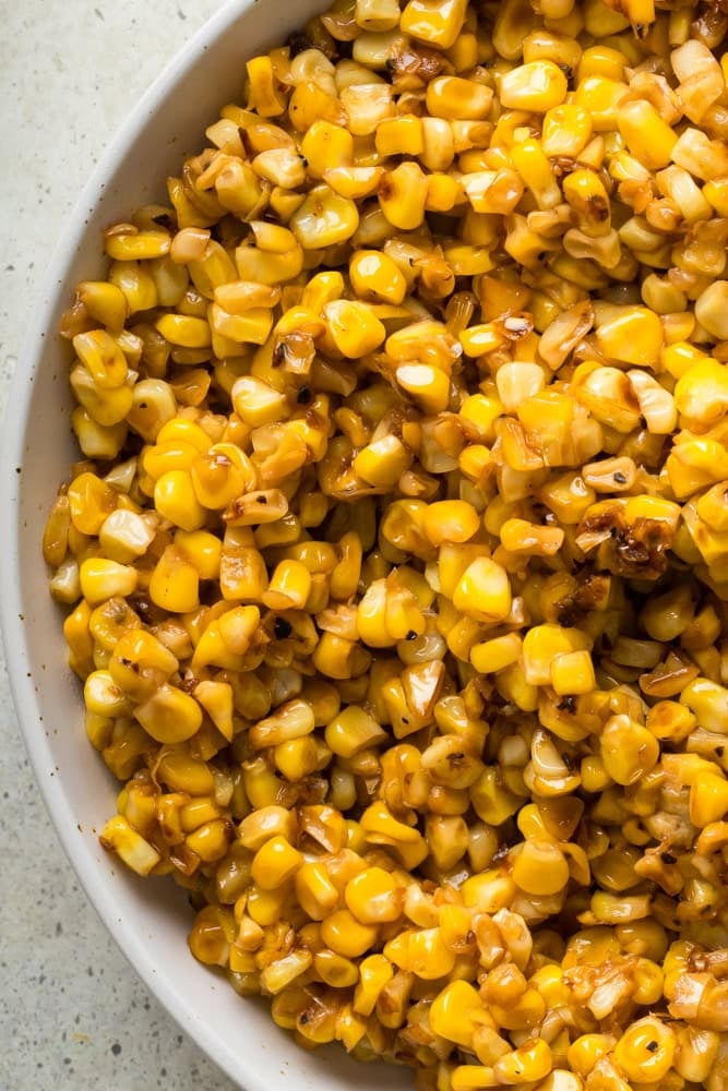 Overhead close-up of buttery fried corn with yellow kernels and caramelized brown spots.