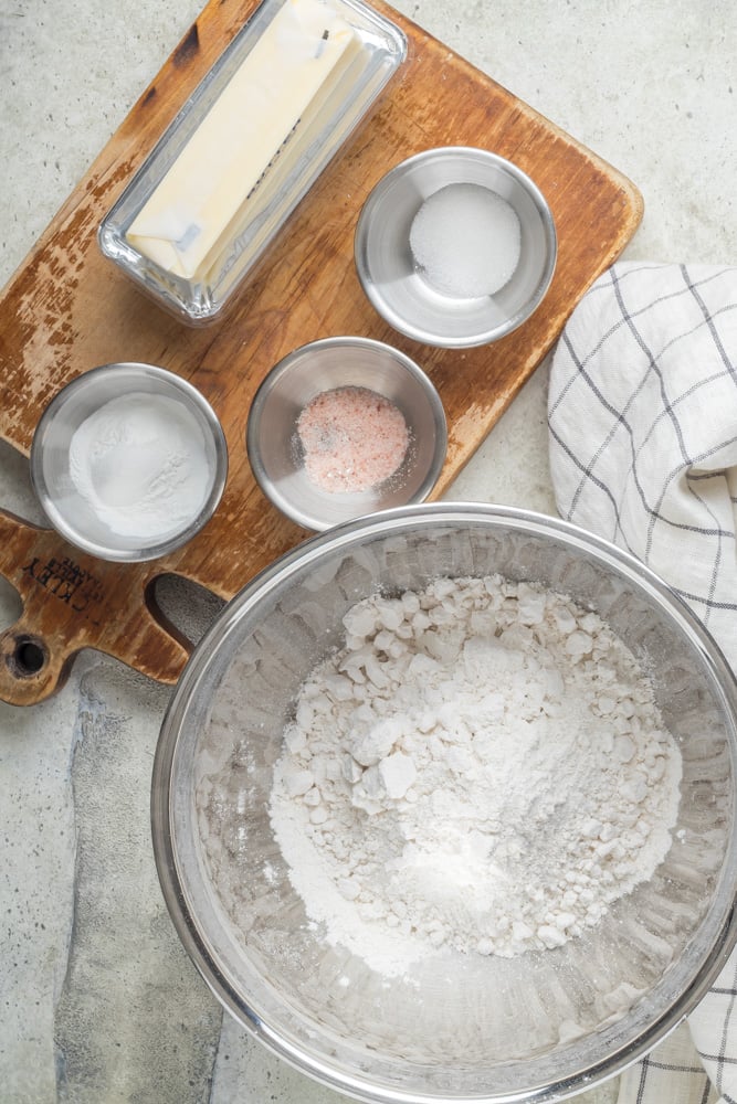 Flour, butter, and measured dry ingredients arranged for making homemade biscuits from scratch.