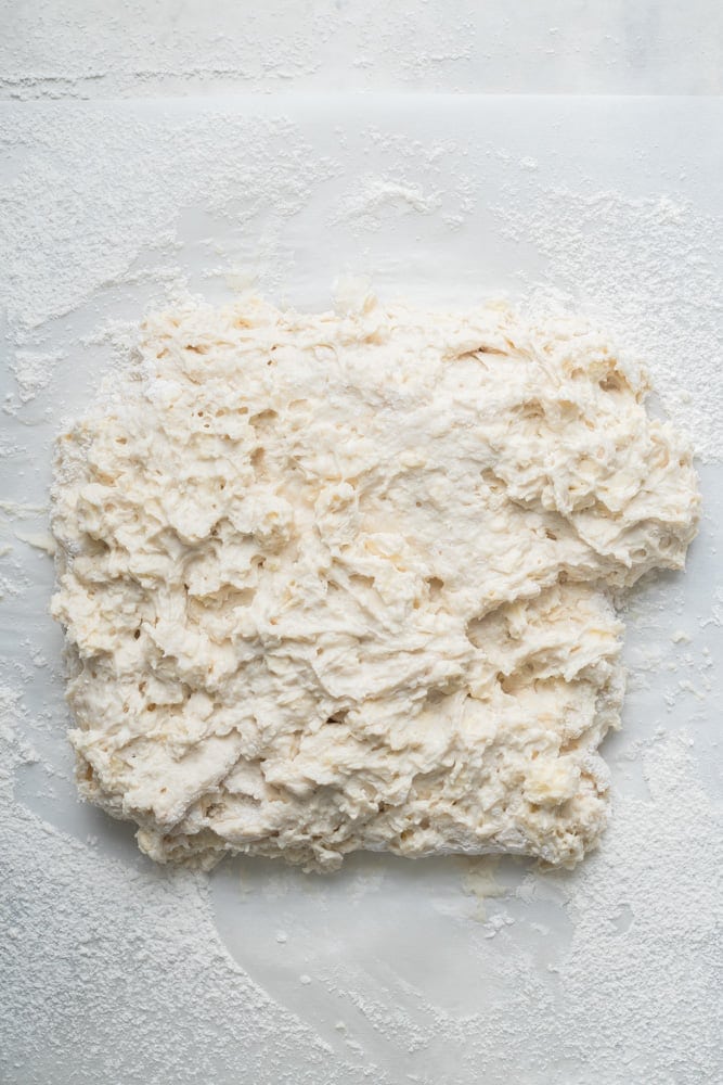 Soft, shaggy homemade biscuit dough turned onto a floured work surface.